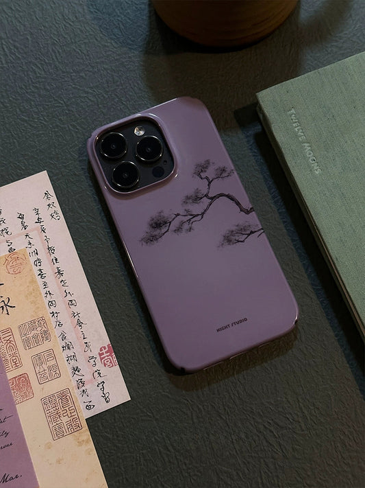 A waterproof phone case with a pine tree design, placed on a table alongside a note and a book.