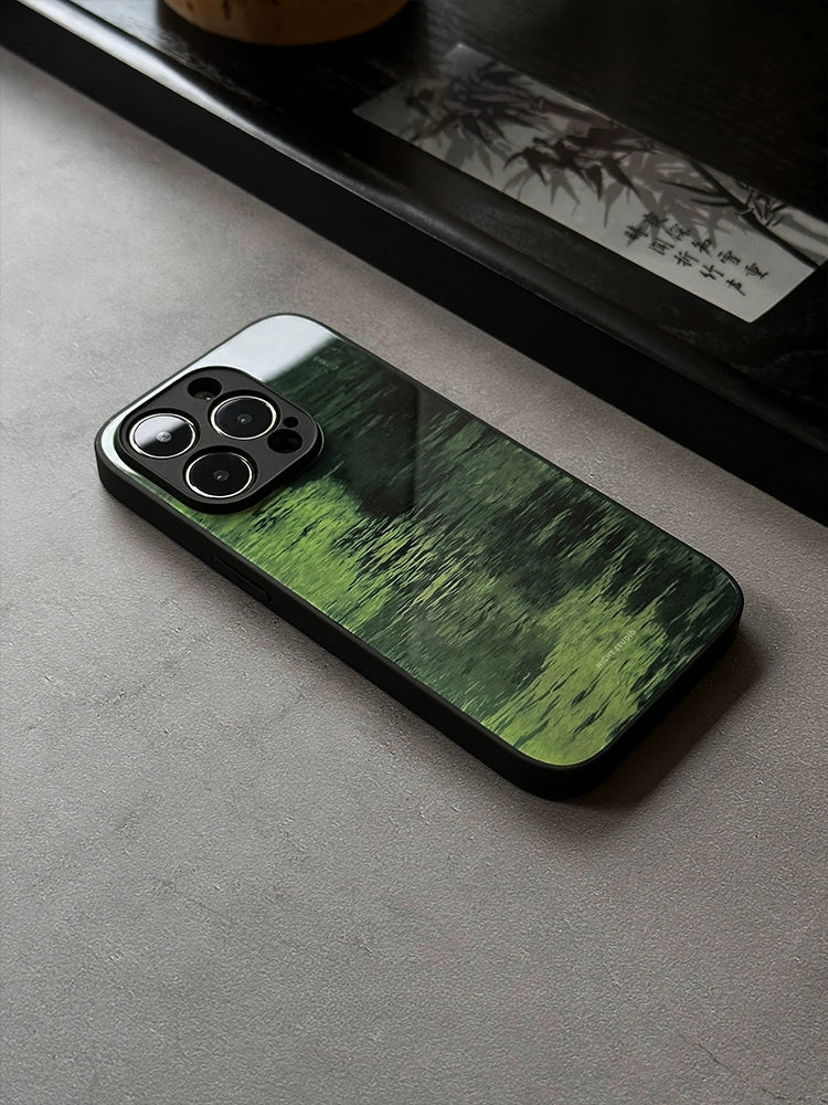 A phone case with a green lake design, placed on a flat surface, showcasing the back side of the case with the phone's camera and buttons visible.
