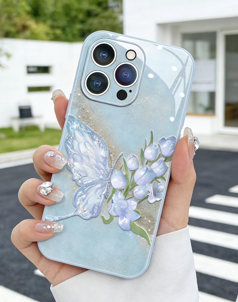 Light Phone case with butterfly and floral design held by a person outdoors.