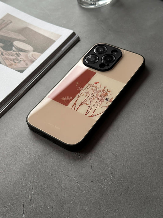 A phone case with a vintage Chinese art painting design, placed on a flat surface next to some photos and a glass.