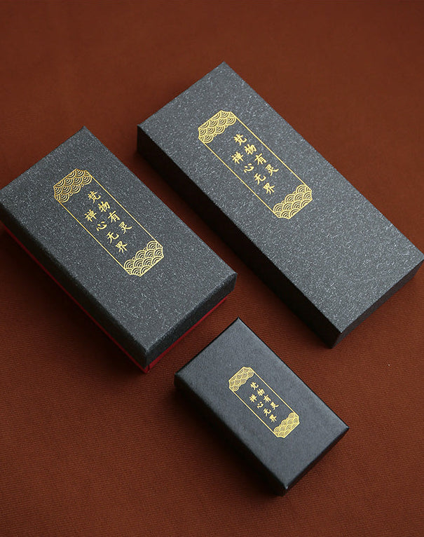 Three black boxes with gold accents on a brown background