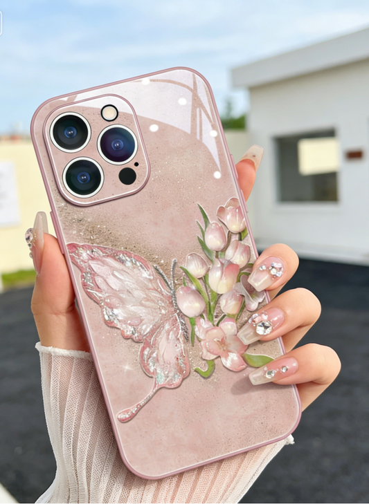 Pink Phone case with butterfly and floral design held by a person outdoors.